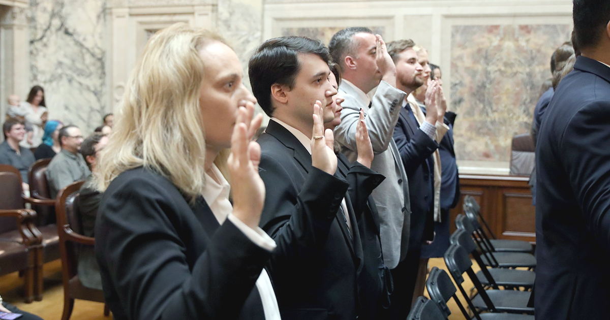 a line of people hold their hands up taking an oath