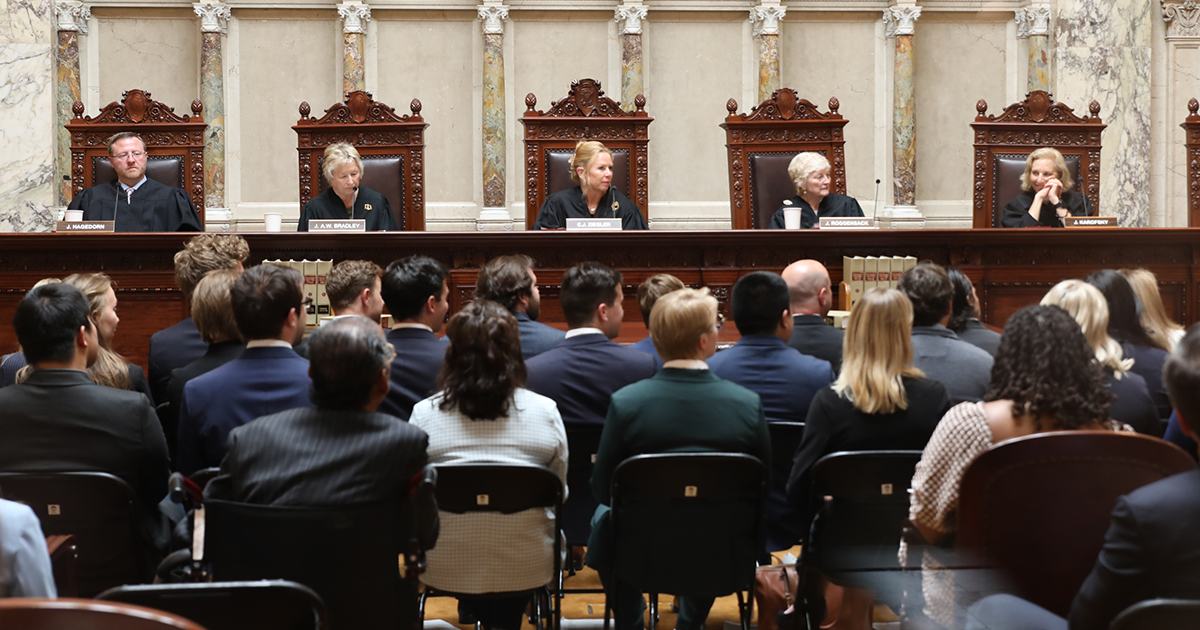 five justices sit at the bench before a crowded room