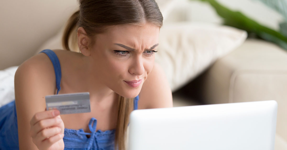 woman holding credit card staring at computer screen