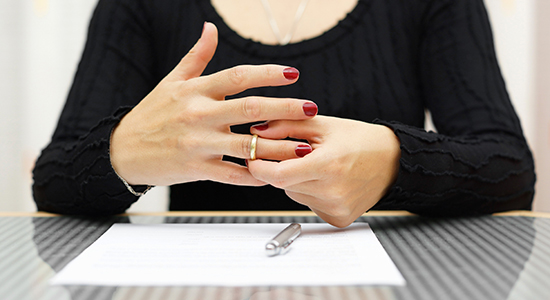 woman signs divorce papers and removes ring