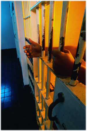 Photo: Hands behind prison   bars