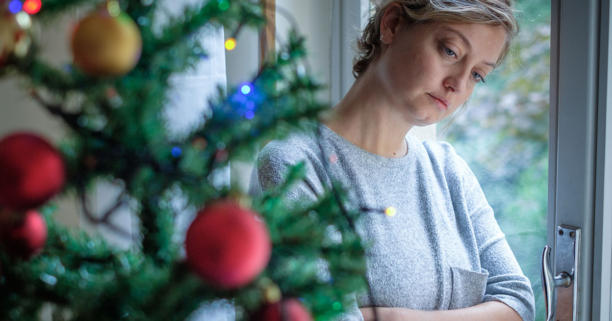 depressed woman stands behind holiday decoration