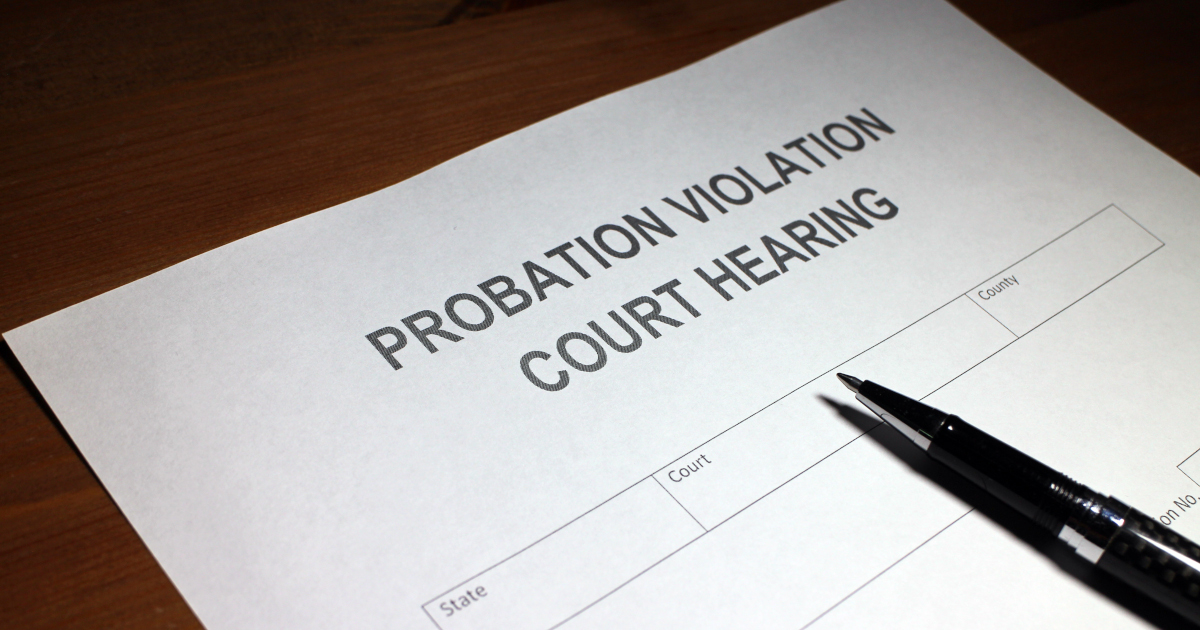 A Probation Violation Court Hearing Form With A Black Ballpoint Pen Lying Across It