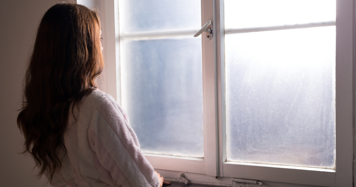 Woman With Long Brown Hair Staring Out Window of A Mental Hospital