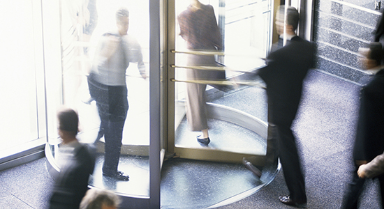 business people walking through revolving door