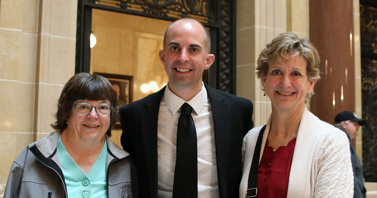 three people smile at the camera