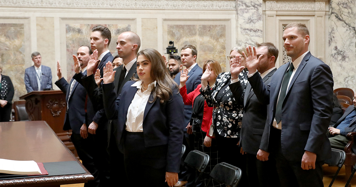 a group stands with hands up taking an oath