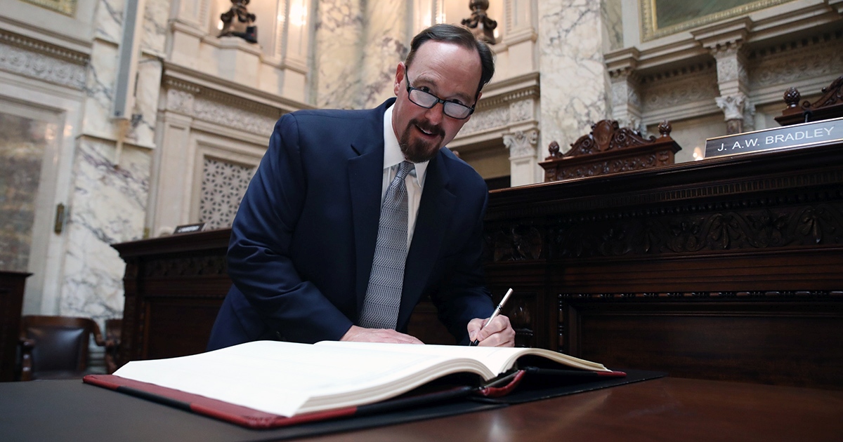 a man smiles at the camera while holding a pen