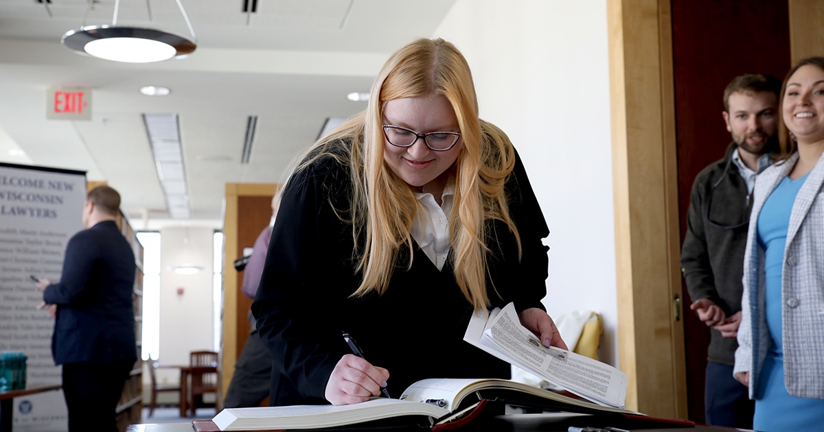 a woman smiles as she writes in a large book