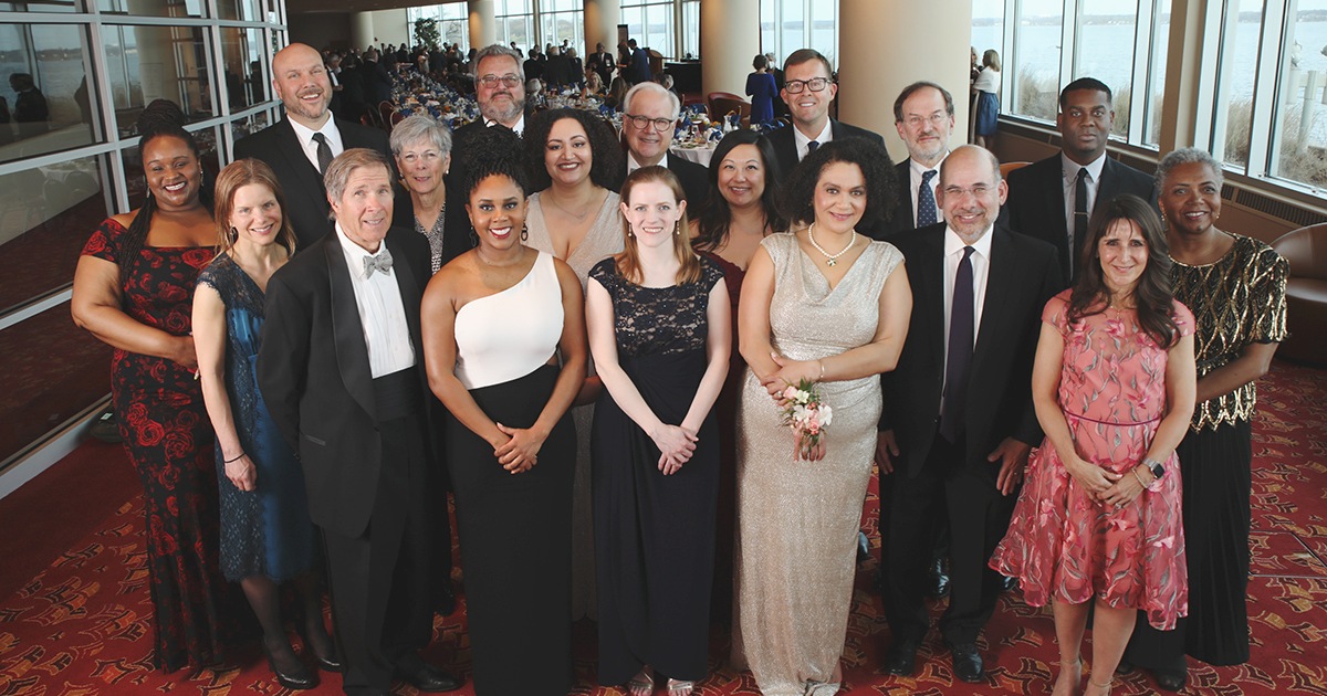 a group of 18 people smiling at the camera