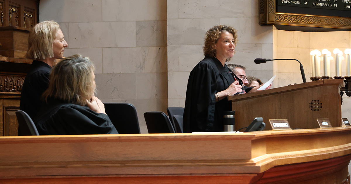 a woman at a podium smiles at the audience