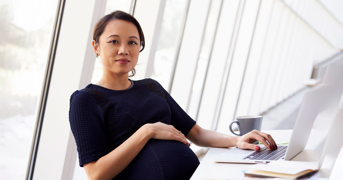 pregnant employee sits at computer
