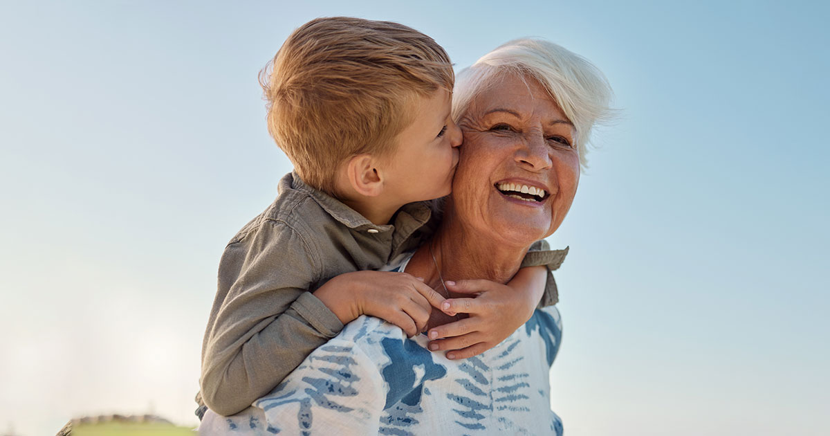 grandmother carries grandson who kisses her on the cheek