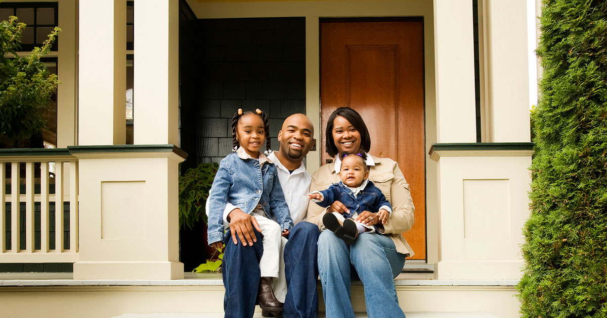 family sits on front step of their house