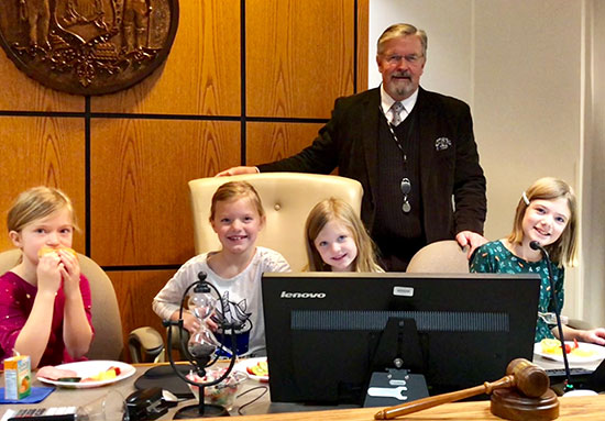 Judge Rod Smeltzer stands behind his bench with his four granddaughters