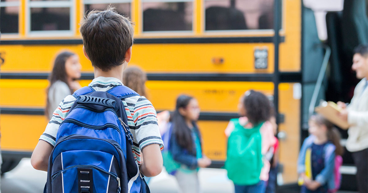 elementary age child walking up to school bus