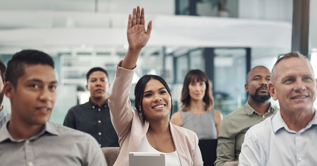 professional raises her hand in a meeting