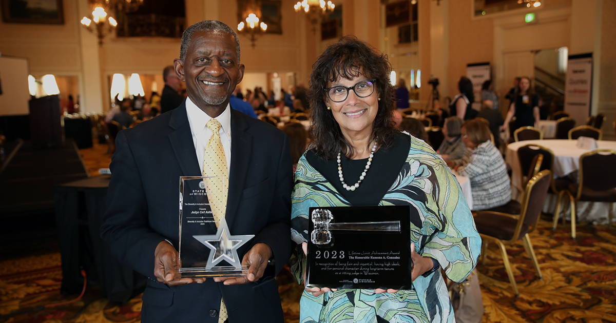 two people smile at the camera holding awards