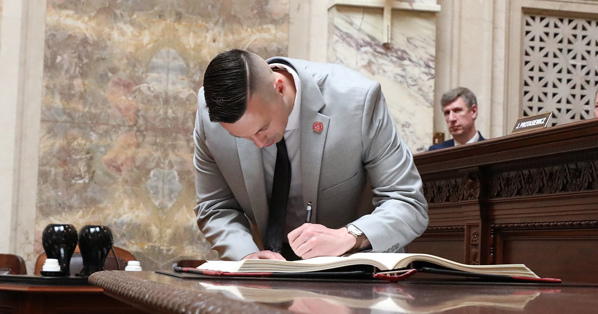 a man leans over while writing in a book