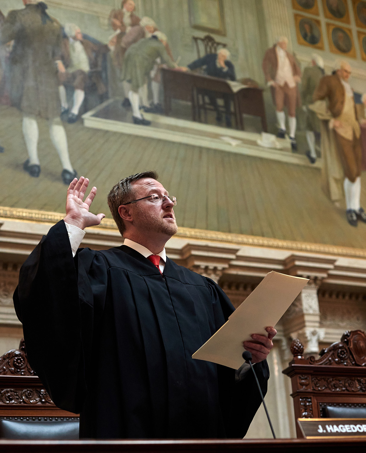 a man stands with hand raised