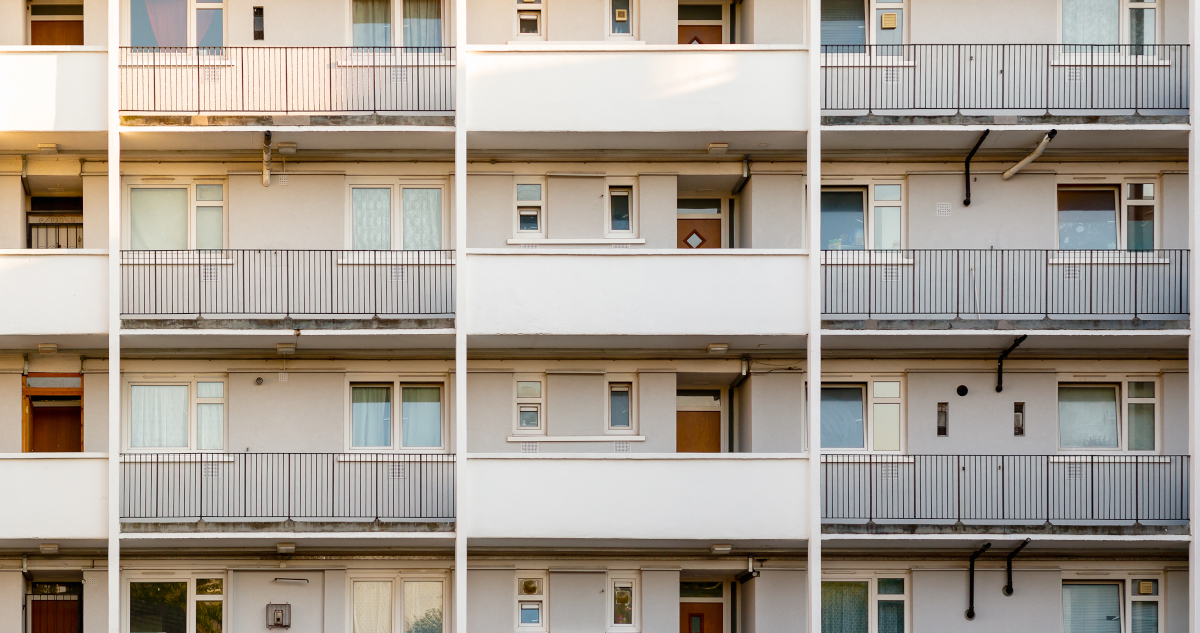 A Large Block of Drab Apartments With Front Doors Opening On to Patios, Seen From Head On