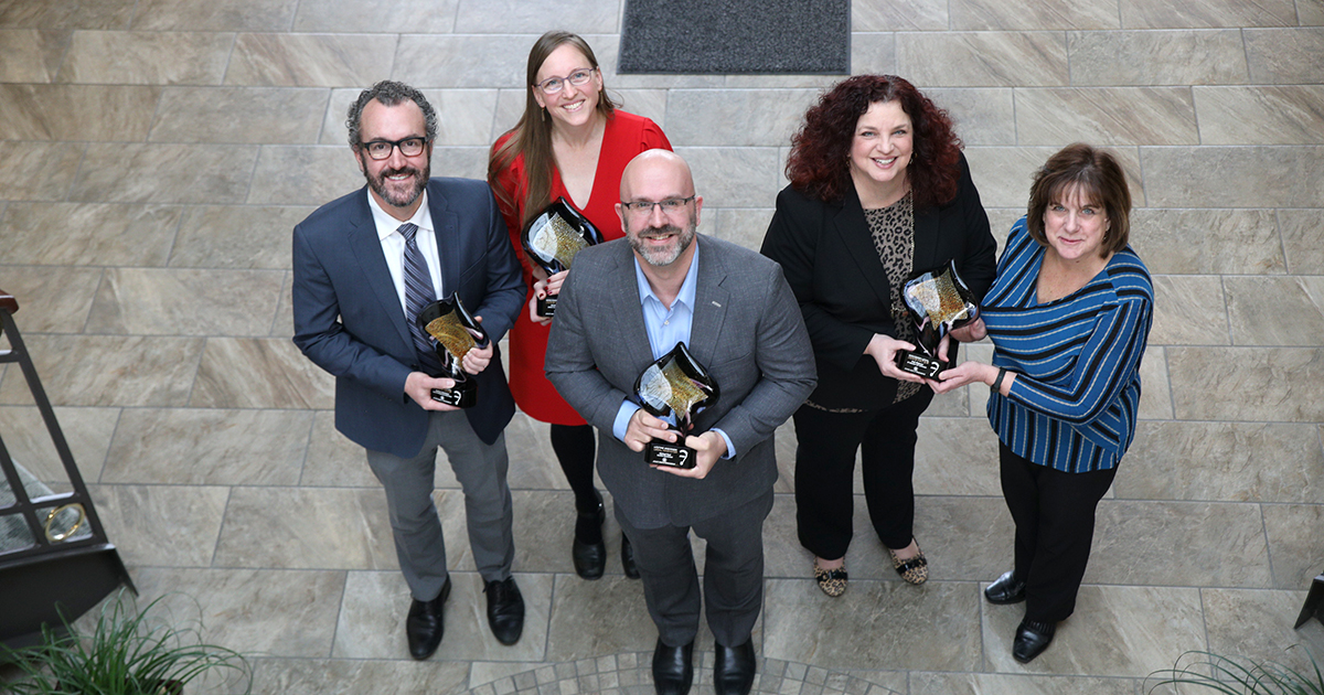 six people hold their Legal Innovator awards and smile at the camera