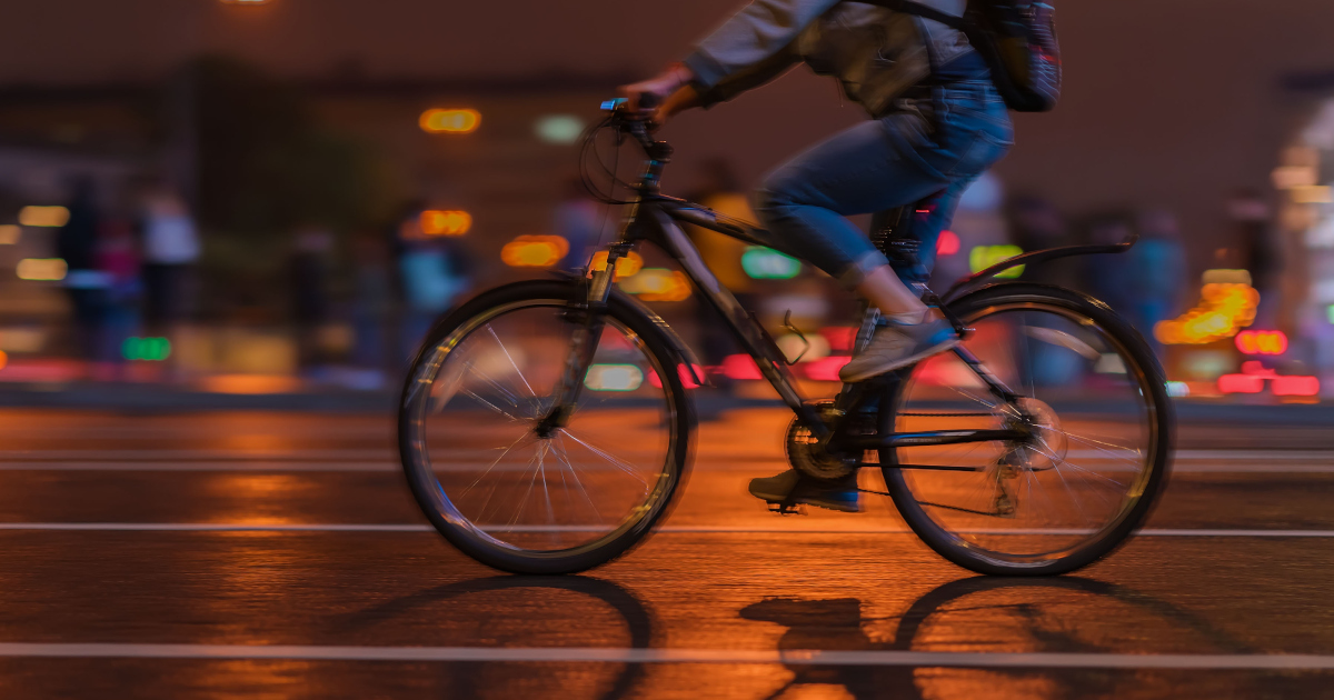 Person Riding A Bike Down City Street At Night