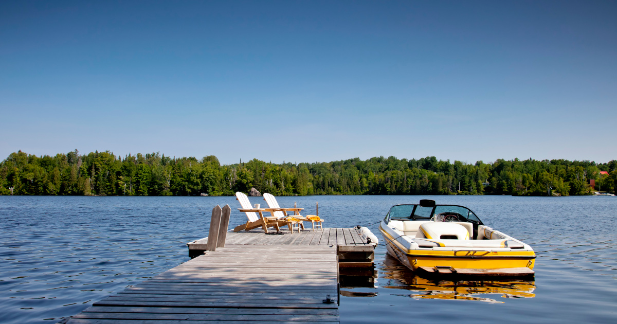 A Yellow Runabout Boat Tied Up To A Pier On A Lake