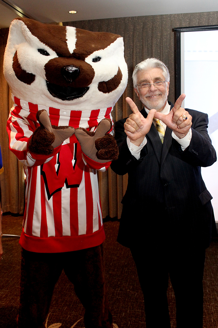 Bucky Badger and a smiling man hold their hands up in the W symbol for UW-Madison