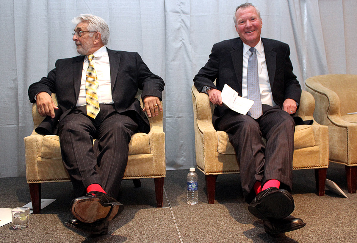 two men seated on a stage, both wearing red socks