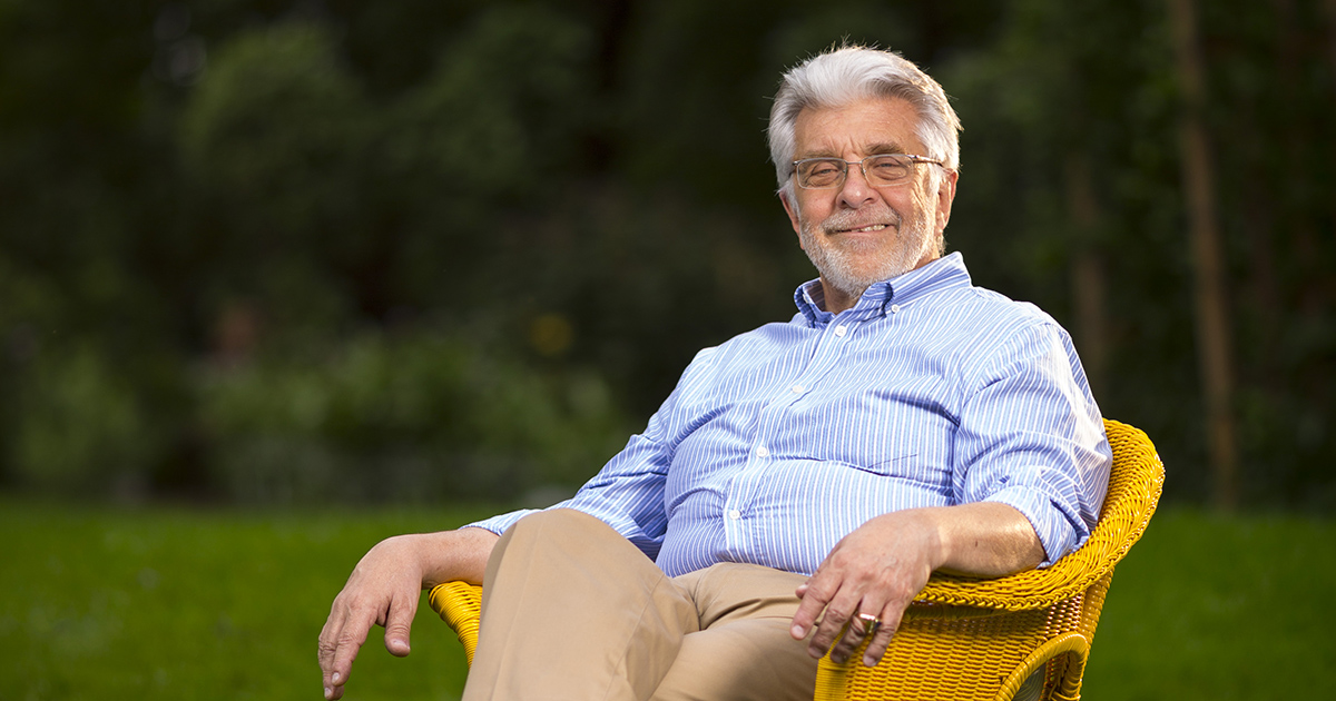 a portrait of Ralph Cagle sitting in a wicker chair on a green lawn