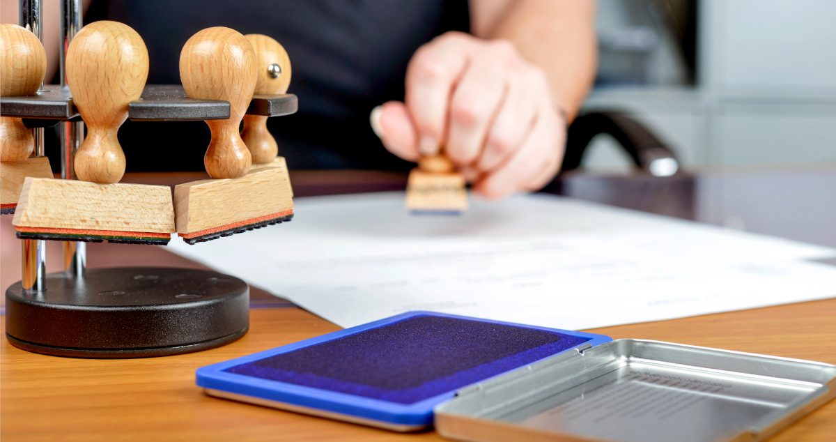 A Woman’s Hand Stamping A Document With An Ink Stamp