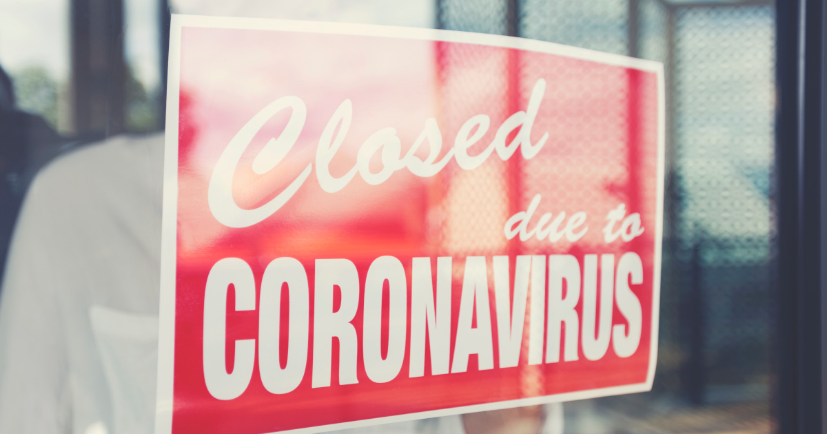 A Red Sign With White Lettering That Reads “Closed Due to Coronavirus Hanging In A Shop Window