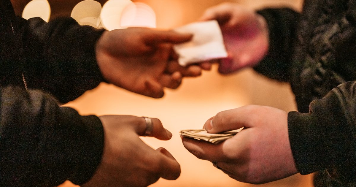 A Close Up Of Two Men Exchanging A Wad Of Cash For A Packet Of Powder, Backlight by Orange City Light