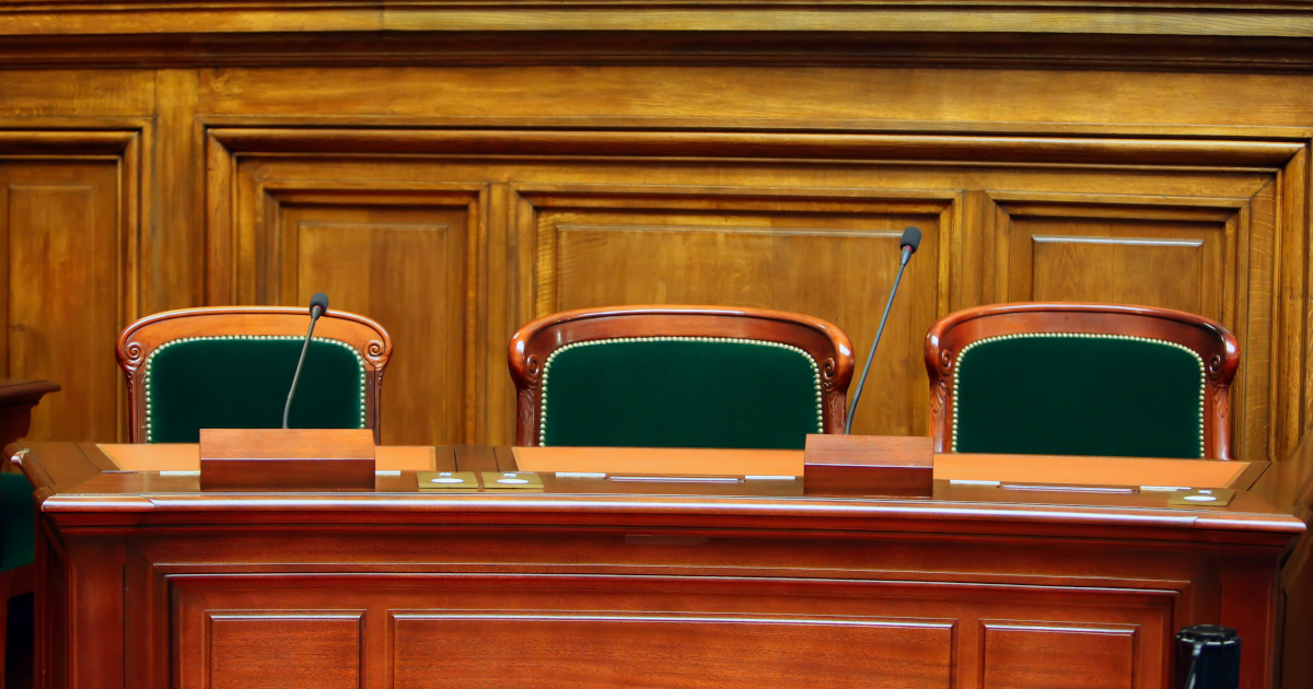 Mahogany Chairs with Beize Backs In Front Of A Mahogany Table Outfitted With Microphones