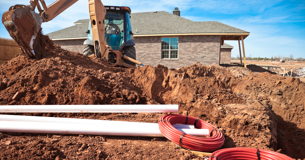 Pipes Next To A Pile Of Dirt And A Trench Behind A House