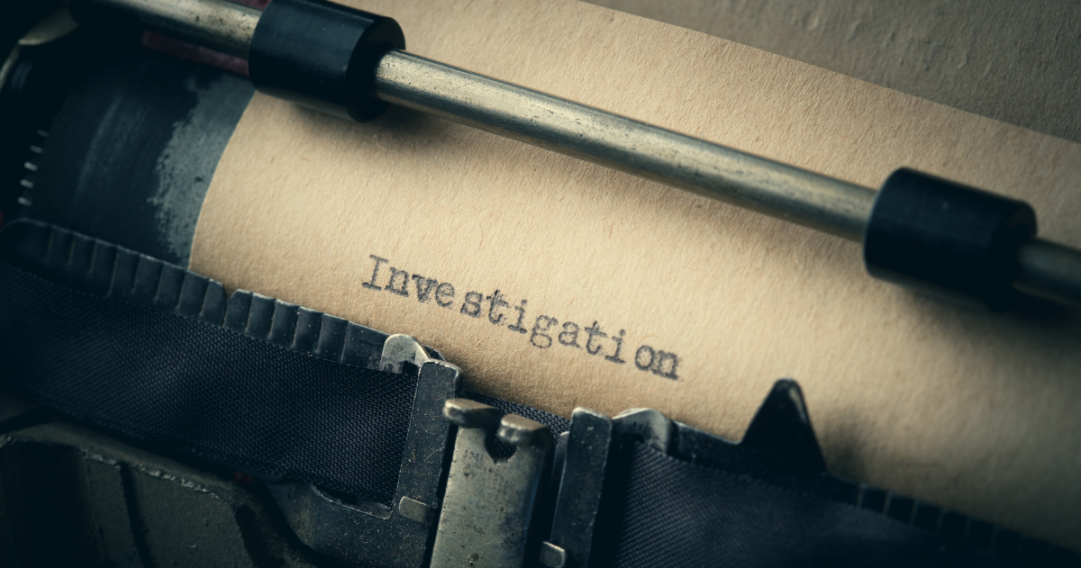 A Piece of Paper Slotted Into The Platen Of A Black Typewriter, With The Word Investigation Typed Across The Top