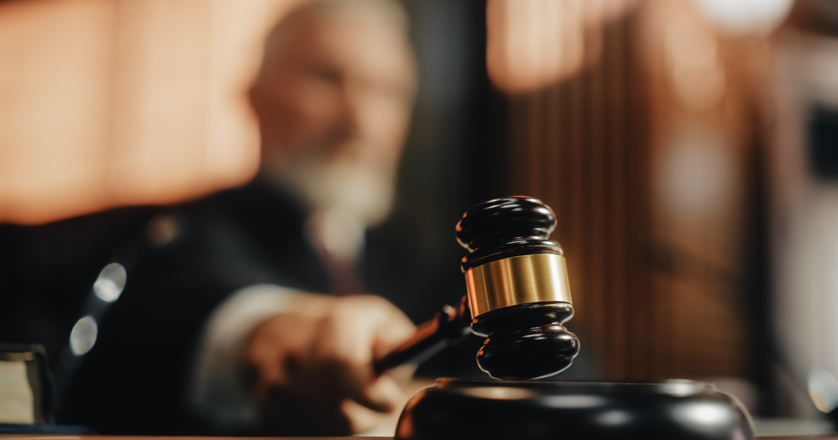 A White Bearded Judge Reaches Forward To Gavel A Hearing To Conclusion
