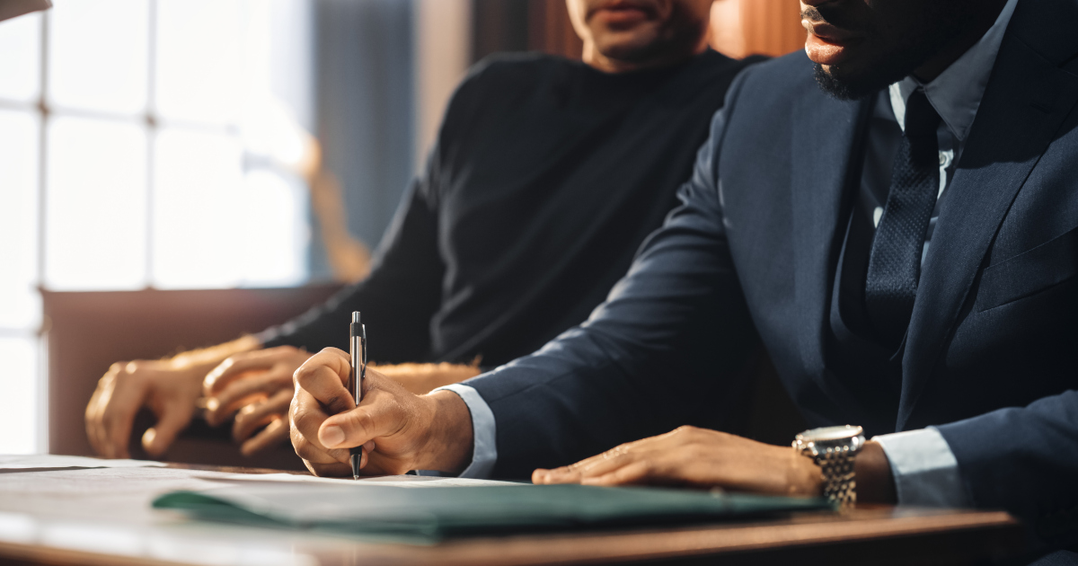 A Criminal Defendant And His Attorney Sitting At  A Table In A Courtroom