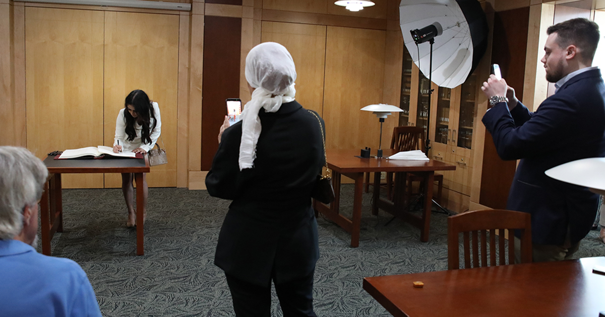 a Marquette law grad signs a book while others take photos