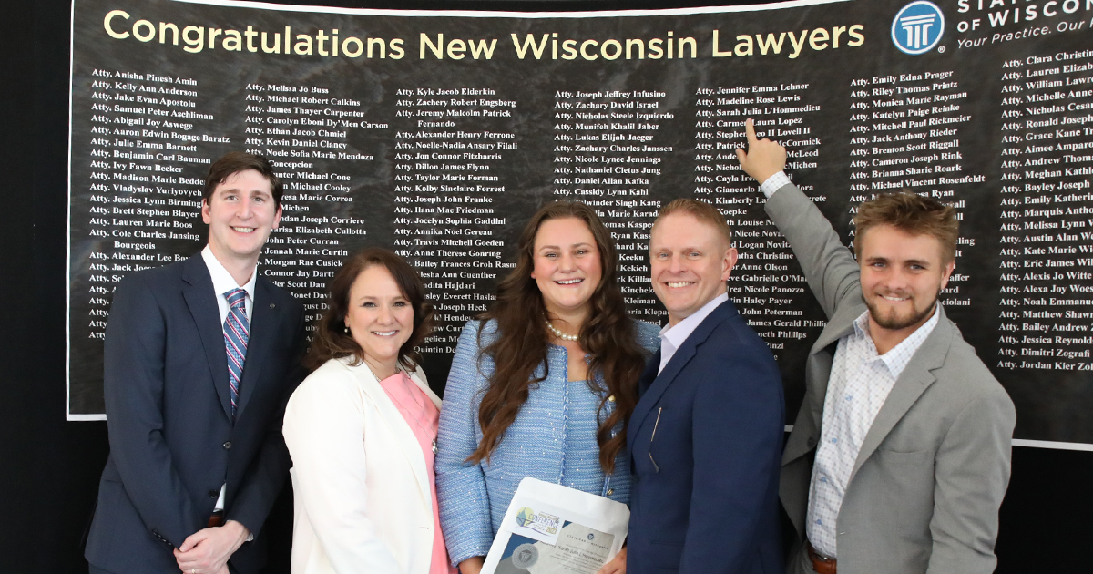 a Marquette law grad signs a book while others take photos