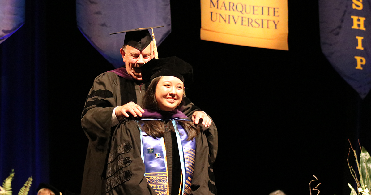 Two people on a stage in academic regalia