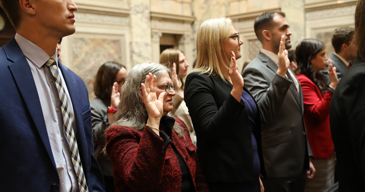 a group of people with right hands raised, taking an oath