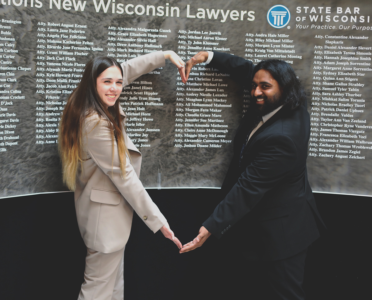 Two people stand with their arms held together in a heart shape