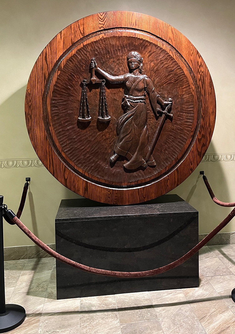 a large circular wood carving stands on a pedestal base