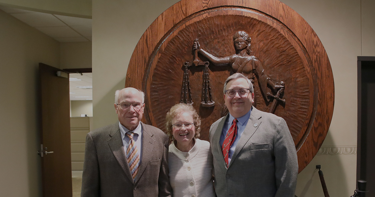 three people pose smiling and standing side by side