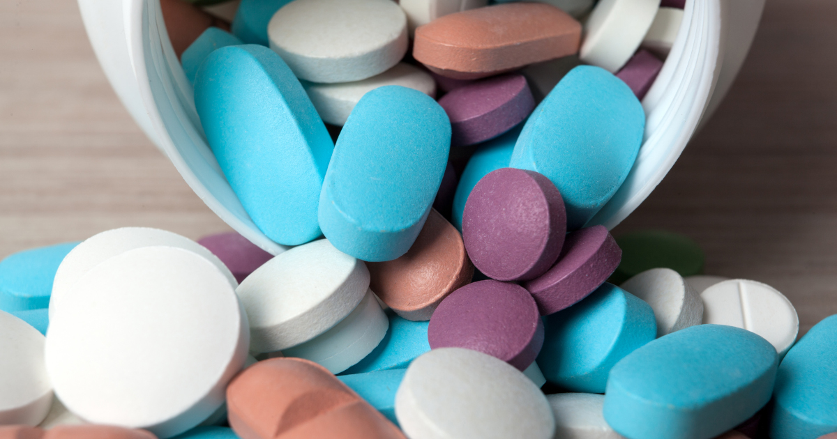 Tablets In Various Colors Spilling Out of Pill Bottle