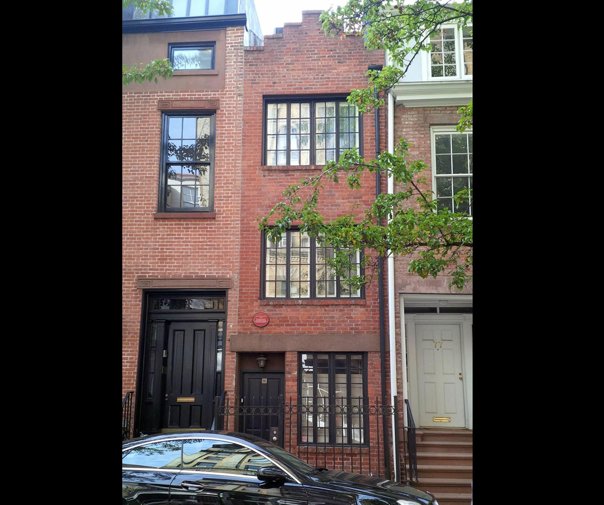 A very narrow multiple story house between regular sized buildings