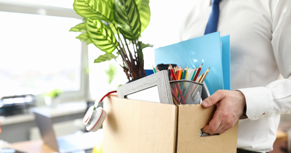 A Man Hauling Items Away From His Desk In A Banker’s Box