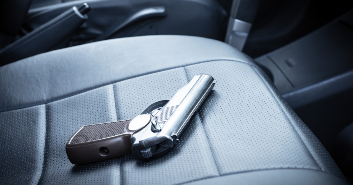 A Large Black Automatic Pistol Lying On The Front Passenger Seat Of An Automobile